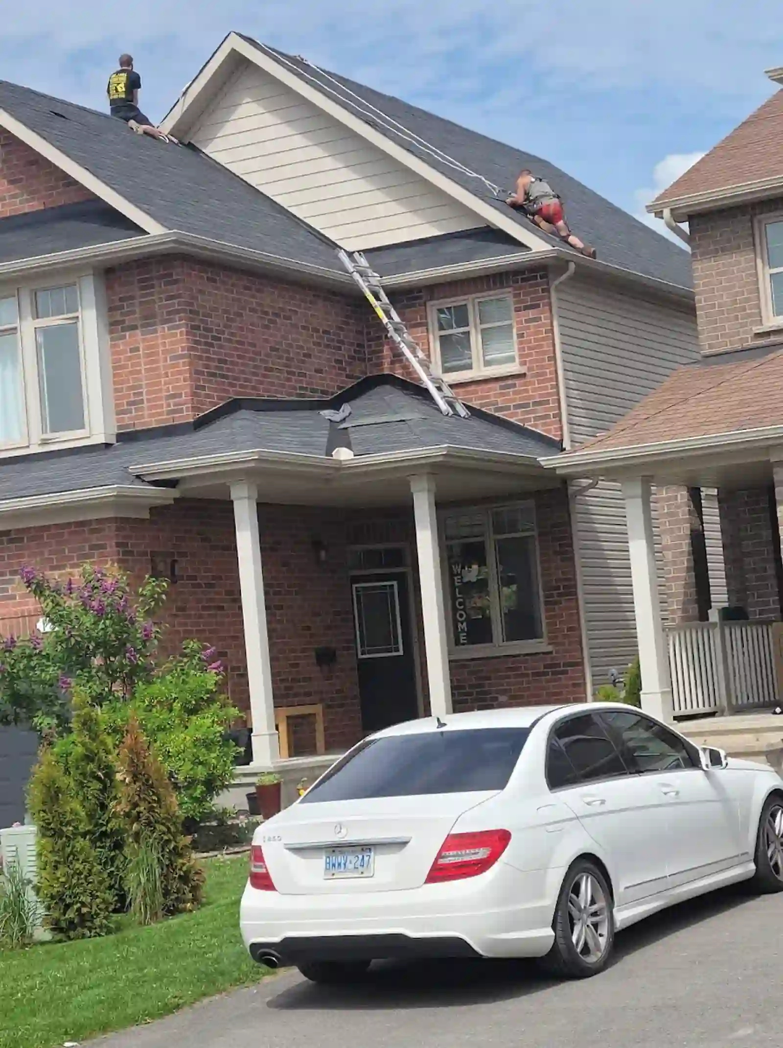 Two roofers working on a two-storey house roof