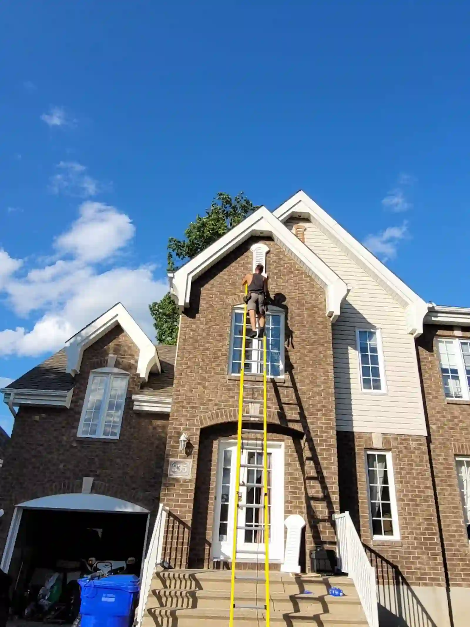 Worker on ladder at a brick house gable vent