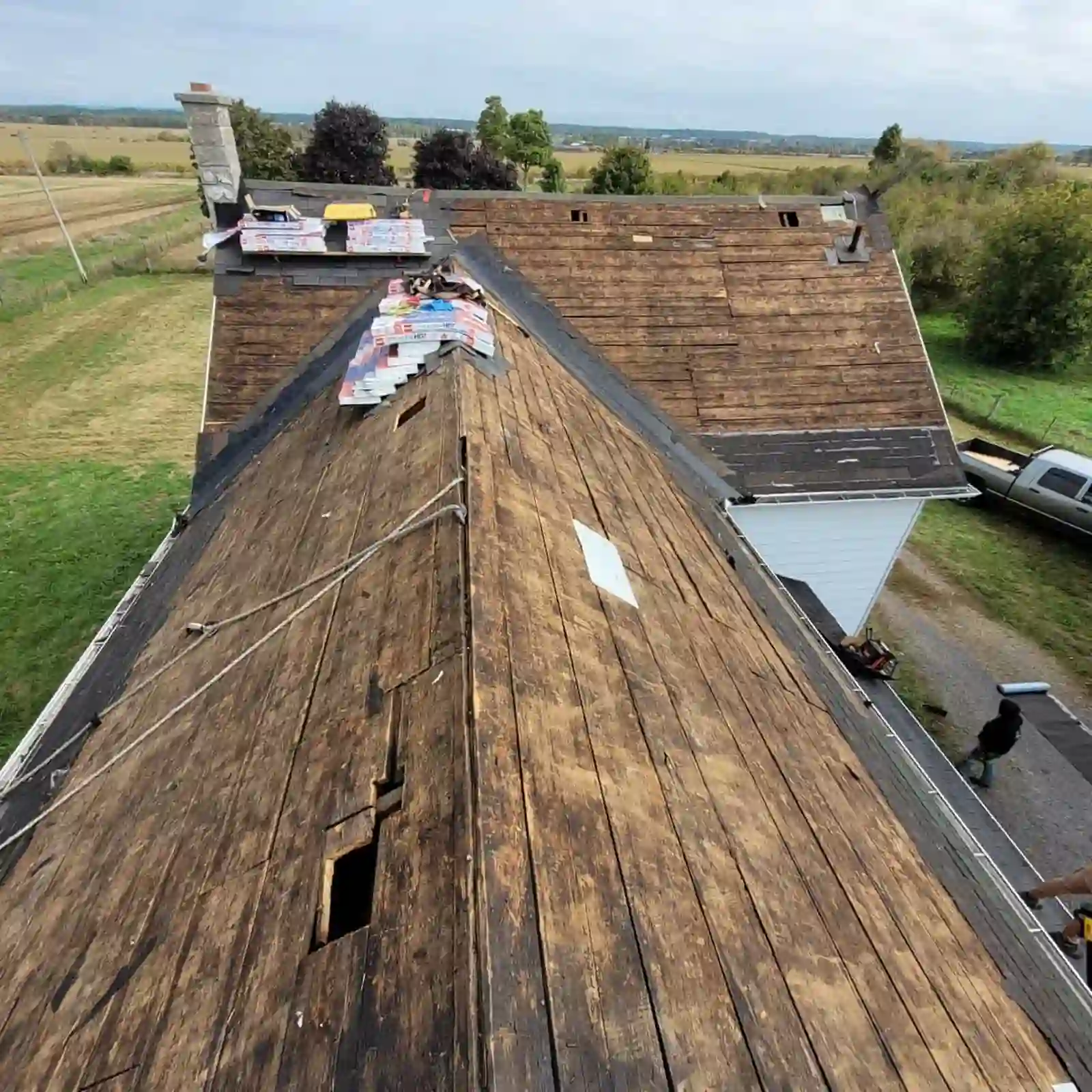 Roof tear-off with plywood deck and new shingle bundles staged